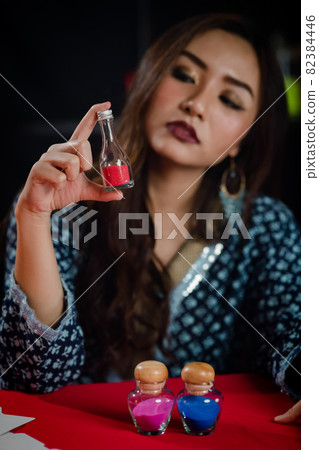 Asian witch examining magic ingredients Asian witch examining magic ingredients 82384446