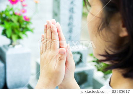 A woman holding hands in front of the grave 82385617