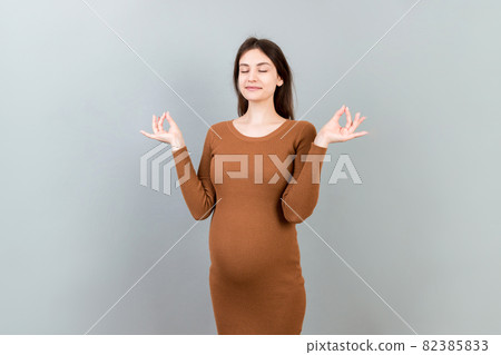 Smiling pregnant woman standing and practicing yoga isolated on colored background Smiling pregnant woman standing and practicing yoga isolated on colored background 82385833