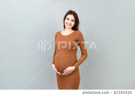 Happy pregnant woman touching her abdomen at Colored background. Future mother is wearing white underwear. Expecting of a baby. Copy space 82385838