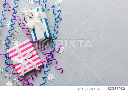 Holiday flat lay with gift boxes wrapped in colorful paper and tied decorated with confetti on colored background. Christmas, Birthday, Valentine and sale concept, top view 82385980