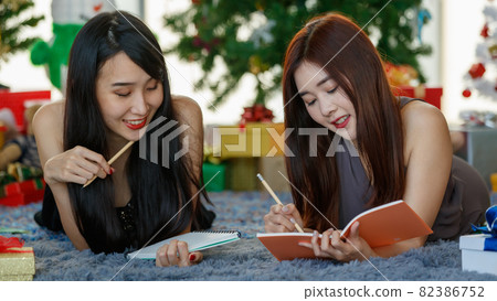 Asian girlfriends writing down Christmas wishes Asian girlfriends writing down Christmas wishes 82386752