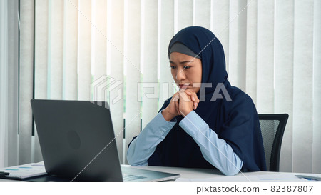 Muslim woman looks at a computer screen and gets stressed. 82387807