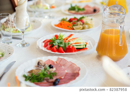 Sliced vegetables and cold cuts on a plate served on a table in a restaurant for a banquet 82387958