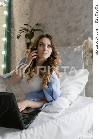 work at home: a girl in bed with a laptop. businesswoman connect with smartphone. remote work. shop on the couch. shopping via the internet work at home: a girl in bed with a laptop. businesswoman connect with smartphone. remote work. shop on the couch. shopping via the internet 82388008
