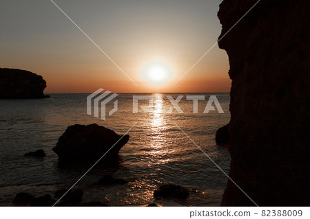 waves wash the rocky shore of the sea. Sunset. Reflection in the water of the bridge and rays 82388009