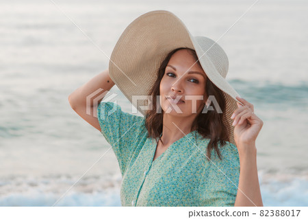 journey to the sea. a girl in a dress and hat is walking along the beach. a tourist walks along the sea coast. hot trips during the holiday period. copy space journey to the sea. a girl in a dress and hat is walking along the beach. a tourist walks along the sea coast. hot trips during the holiday period. copy space 82388017