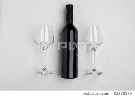 Overhead angled view of a large bottle of red wine, drinking glasses on white background 82388579