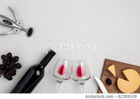 Two wine glasses with red wine,bottle of red wine and cheese on white background.Horizontal view from the top. 82389109