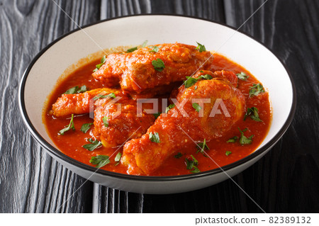 Authentic Ayam Masak Merah Recipe made with chicken pieces that are doused in a spicy tomato sauce close-up in a bowl. Horizontal 82389132