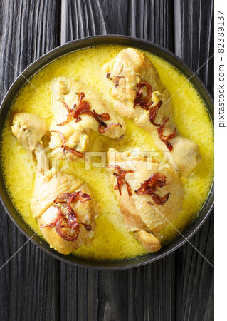 Opor ayam chicken cooked in coconut milk with spices close up in the bowl. Vertical top view 82389137