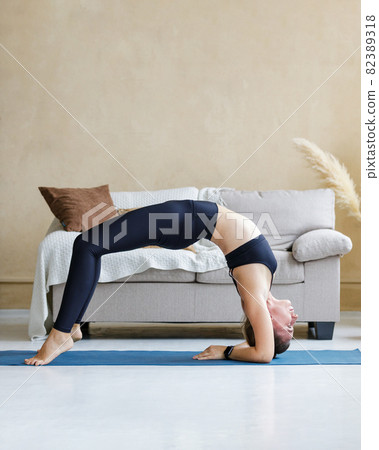 Young woman performing wheel pose during morning yoga routine 82389318