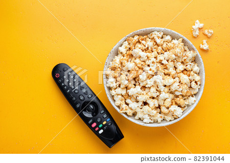 Bowl of popcorn and TV remote control Bowl of popcorn and TV remote control 82391044