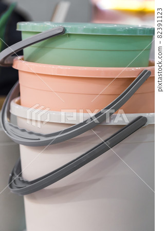 Various plastic new empty buckets stacked. Inventory and household items in trendy pastel colors. Industrial background 82391123