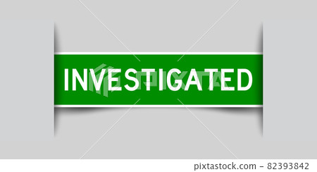Inserted green color label sticker with word investigated on gray background 82393842