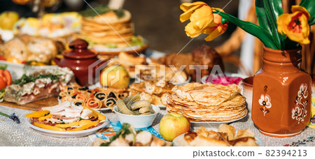 Dishes of the traditional Belarusian cuisine - pancakes, pancakes with caviar, lard, bacon, honey and pickled cucumbers. Attribute of traditional folk celebration of Maslenitsa. Panorama, Panoramic Dishes of the traditional Belarusian cuisine - pancakes, pancakes with caviar, lard, bacon, honey and pickled cucumbers. Attribute of traditional folk celebration of Maslenitsa. Panorama, Panoramic 82394213