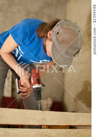 Skilled young female worker is using power screwdriver drilling during construction wooden bench gender equality, feminism, do it yourself concepts. Skilled young female worker is using power screwdriver drilling during construction wooden bench gender equality, feminism, do it yourself concepts. 82394598