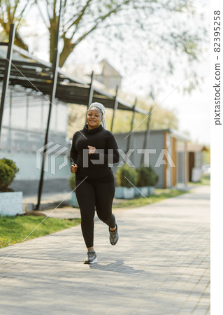 Afro-american plus size woman jogging outdoor Afro-american plus size woman jogging outdoor 82395258