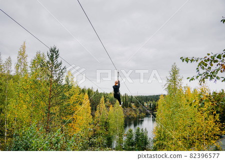 Woman on trolley, equipment on steel cables over a mountain river Woman on trolley, equipment on steel cables over a mountain river 82396577