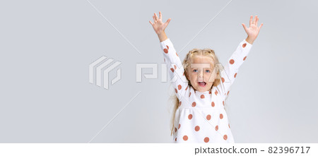 Portrait of little preschool girl posing with raised hands isolated over white studio background. 82396717