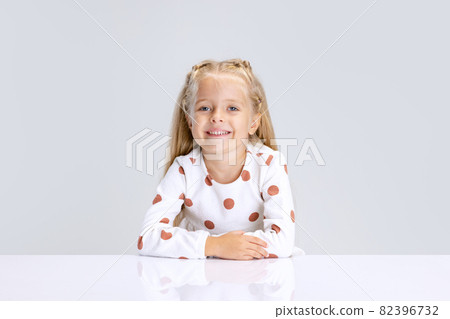 Portrait of little preschool girl, child calmly sitting isolated over white studio background. Portrait of little preschool girl, child calmly sitting isolated over white studio background. 82396732