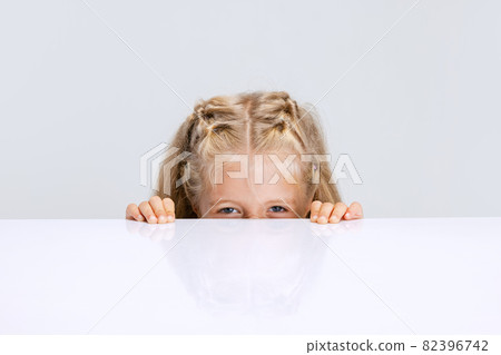 Portrait of little preschool girl, child playing hide-and-seek game isolated over white studio background. 82396742