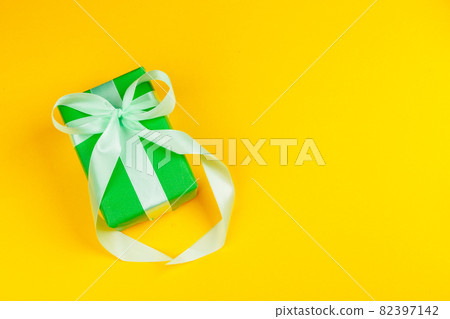 Decorated colored present on yellow background flatlay Decorated colored present on yellow background flatlay 82397142