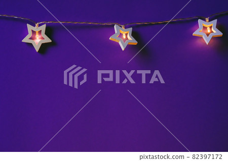 Illuminated star shaped garland on color background close up 82397172