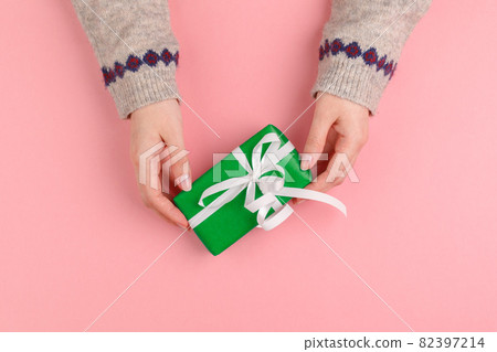 Gift box in female hands on pink background 82397214