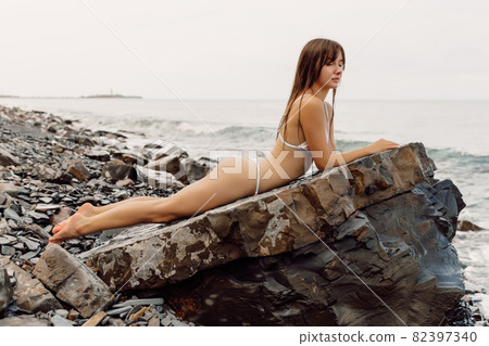 Slim woman in bikini on rock at sea coastline. Caucasian model at vacations Slim woman in bikini on rock at sea coastline. Caucasian model at vacations 82397340
