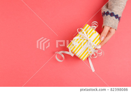 Top view of woman hands holding gift box on pink background Top view of woman hands holding gift box on pink background 82398086