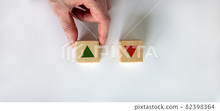 Hand making a choice between two cubes on white background. Wooden cubes changes the direction of an arrow symbolizing that the interest rates are going down or vice versa . Business concept. Copy 82398364