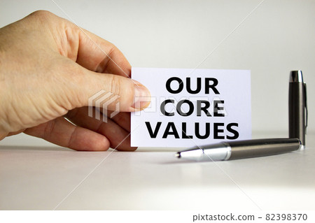 Our core values symbol. White paper with words 'Our core values' in businessman hand, metallic pen. Beautiful white background. Business, our core values concept. Copy space. Our core values symbol. White paper with words 'Our core values' in businessman hand, metallic pen. Beautiful white background. Business, our core values concept. Copy space. 82398370