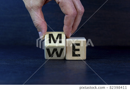 Me or we. Hand turns a wooden cube with me or we words on beautiful dark wooden background, copy space. Psychological and me or we concept. Me or we. Hand turns a wooden cube with me or we words on beautiful dark wooden background, copy space. Psychological and me or we concept. 82398411