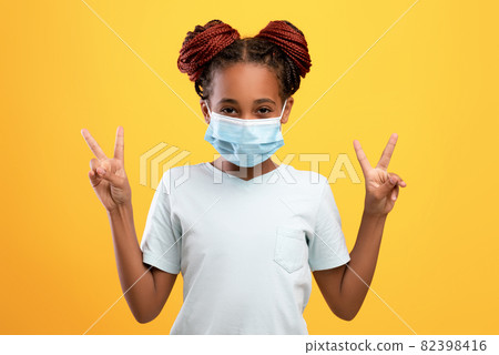 Cute african american girl in face mask showing peace gesture 82398416