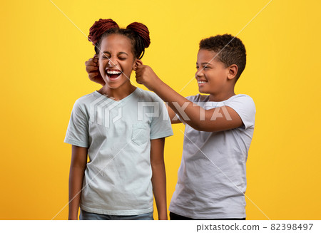 Naughty black boy pulling his sister ears 82398497