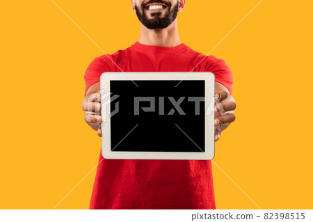 Delivery Guy Showing Digital Tablet Screen Over Yellow Background, Cropped Delivery Guy Showing Digital Tablet Screen Over Yellow Background, Cropped 82398515