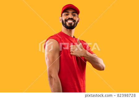 Happy Vaccinated Worker In Red Uniform Gesturing Thumbs-Up, Yellow Background 82398728