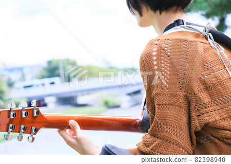 Short-haired girl playing acoustic guitar Short-haired girl playing acoustic guitar 82398940