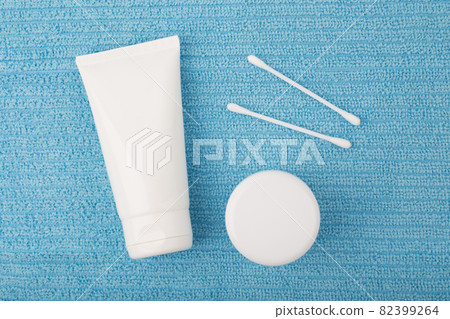 Face cream or cleaning foam, under eye cream or balm and cotton swabs on blue towel 82399264
