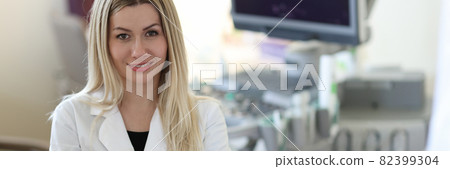 Portrait of young woman doctor sonographer in medical office with patient 82399304