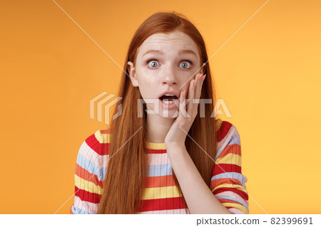 Concerned worried ginger girl blue eyes drop jaw gasping touch cheek confused looking nervously anxious, show empathy hearing terrible upsetting story standing orange background Concerned worried ginger girl blue eyes drop jaw gasping touch cheek confused looking nervously anxious, show empathy hearing terrible upsetting story standing orange background 82399691