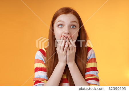Excited shocked redhead speechless girl like gossiping standing emotional astonished hear amusing story gasping full disbelief cover mouth palm amazed posing orange background impressed 82399693