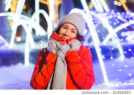 Winter holiday season. Christmas, New Year concept. Funny happy woman spend time having fun near illuminated and decorated showcase on city street. Winter holiday season. Christmas, New Year concept. Funny happy woman spend time having fun near illuminated and decorated showcase on city street. 82400483