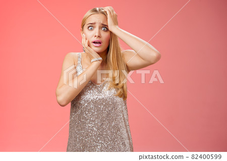 Shocked frightened insecure panicking woman blond hairstyle in silver dress touch head pop eyes afraid scared seing terrifying crime standing stupor speechless gasping shook, red background Shocked frightened insecure panicking woman blond hairstyle in silver dress touch head pop eyes afraid scared seing terrifying crime standing stupor speechless gasping shook, red background 82400599