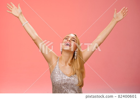 Waist-up carefree happy girl fulfill dream raising hands up sky joyfully close eyes smiling celebrating good perfect news triumphing achieve success victory, standing thrilled red background 82400601