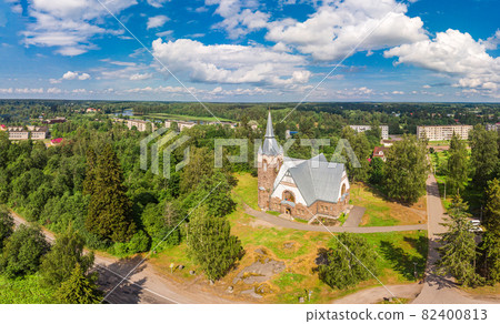 Aerial panoramic view to old lutheran church kirk Ryaysyalya designed by architect Joseph Stenback in style of Finnish romanticism, Art Nouveau in sunny summer day. Melnikovo, Leningrad region, Russia Aerial panoramic view to old lutheran church kirk Ryaysyalya designed by architect Joseph Stenback in style of Finnish romanticism, Art Nouveau in sunny summer day. Melnikovo, Leningrad region, Russia 82400813