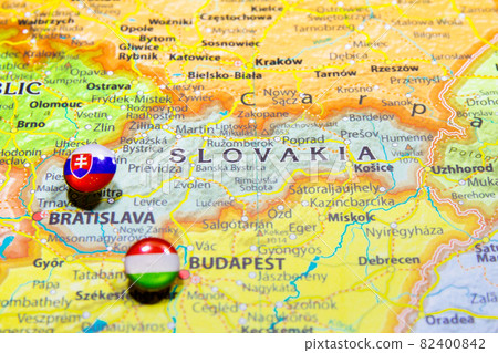 National flag Slovakia pinned on political Europe map. Macro Close up picture on a colorful and blurry world atlas. Capital country - Bratislava. Push pin marker of destination. 82400842