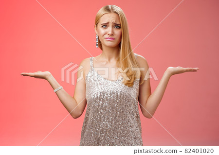Nervous unsure doubtful cute blond woman struggle make decision shrugging pointing sideways frowning upset standing insecure feel pressure cannot decide choice make, frustrated red background 82401020