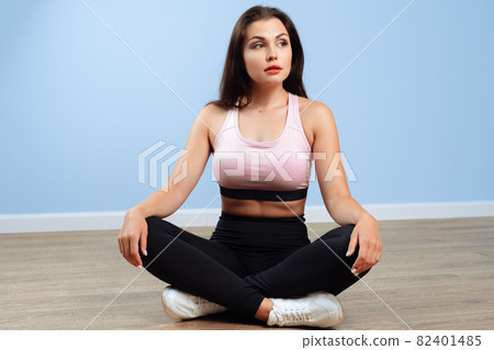 Fit woman in sportswear sitting on the floor in a gym 82401485